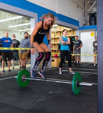 crossfit girls doing burpees over barbell at crossfit competition